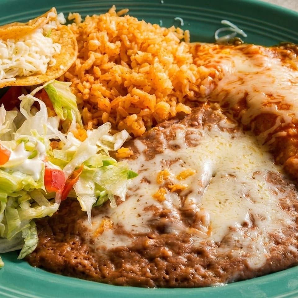 Delicious Mexican combo plate with a cheesy taco, rice, refried beans, enchilada, and fresh salad.